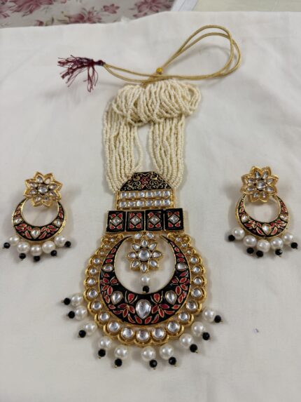 Close-up of kundan pearl necklace pendant with red and black meenakari detailing