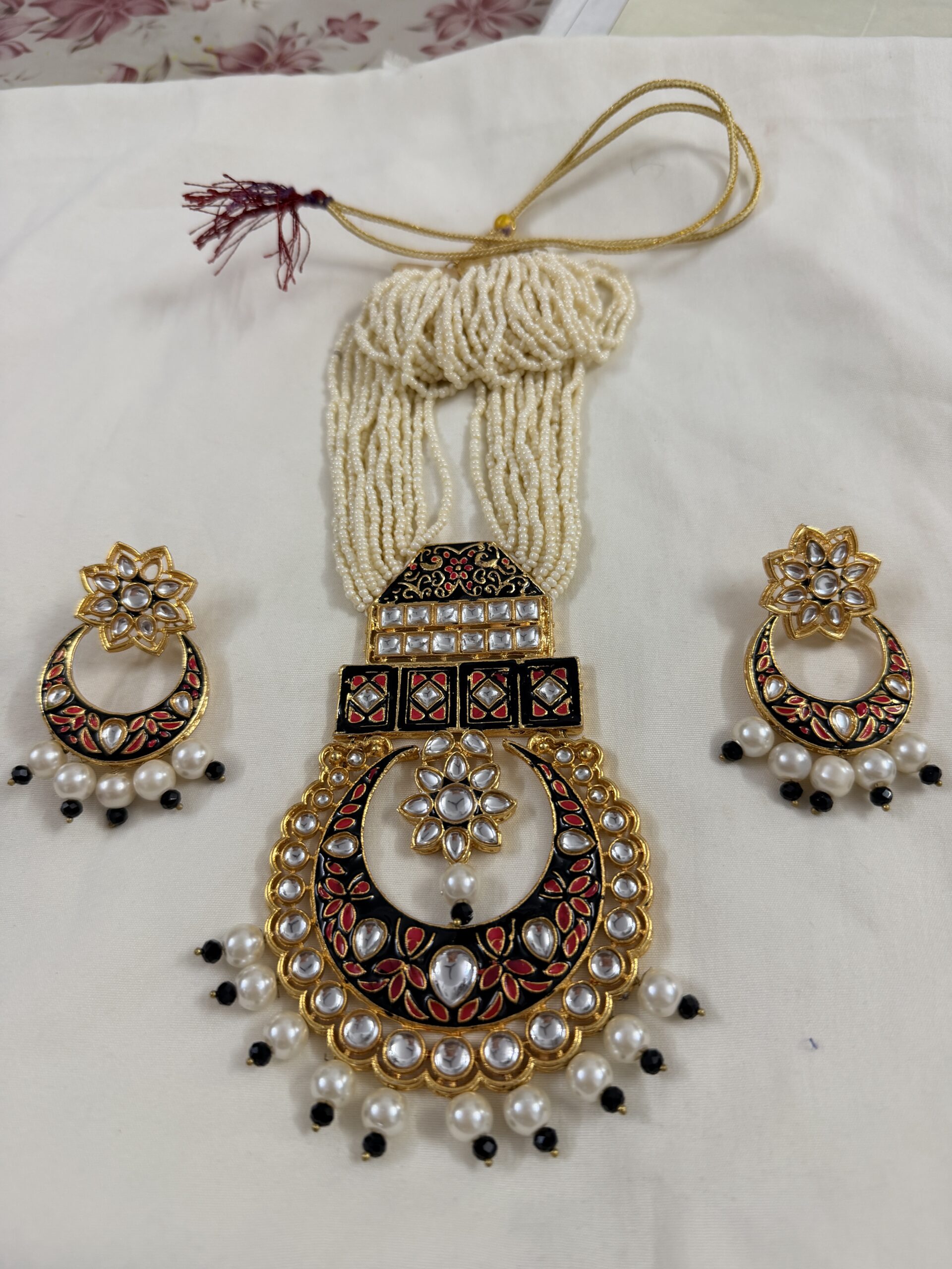 Close-up of kundan pearl necklace pendant with red and black meenakari detailing