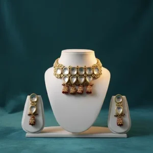 Gold kundan choker necklace set with white stones and red drops on white display stand with matching earrings