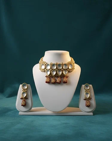 Gold kundan choker necklace set with white stones and red drops on white display stand with matching earrings