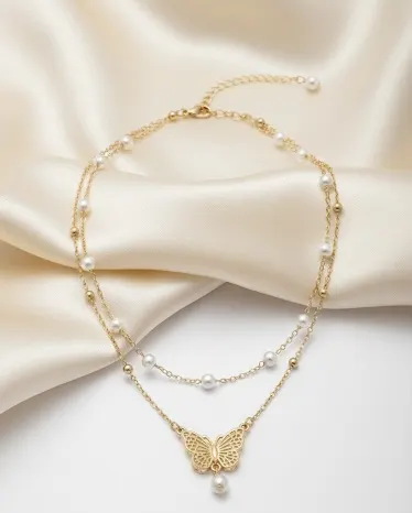 Woman wearing gold butterfly pearl anklet with white outfit - styled ankle jewelry look