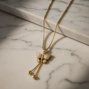 Gold butterfly pendant necklace with crystal wings and black stone on box chain displayed on black background