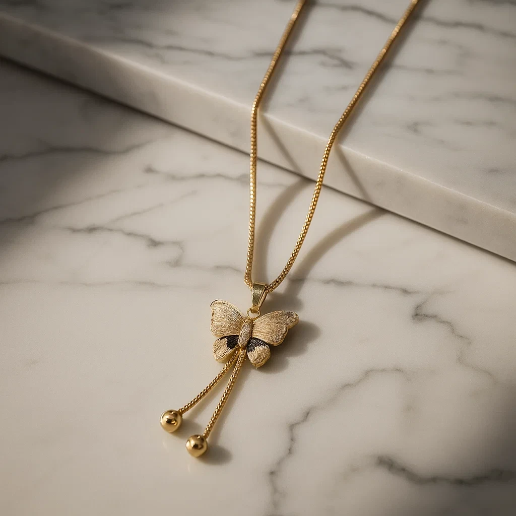 Gold butterfly pendant necklace with crystal wings and black stone on box chain displayed on black background