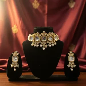 Traditional Indian Kundan choker necklace set with matching earrings displayed on black velvet jewelry stand against navy blue silk backdrop